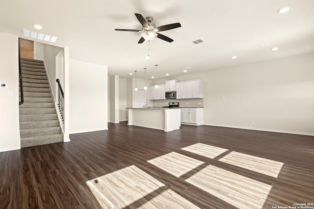 unfurnished living room with ceiling fan and dark hardwood / wood-style flooring