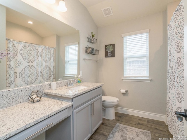 bathroom featuring wood-type flooring, vanity, toilet, and lofted ceiling