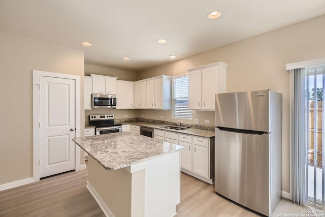 kitchen with a kitchen island, sink, white cabinetry, and stainless steel appliances