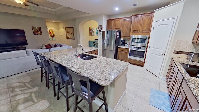 kitchen with sink, a breakfast bar area, appliances with stainless steel finishes, and an island with sink