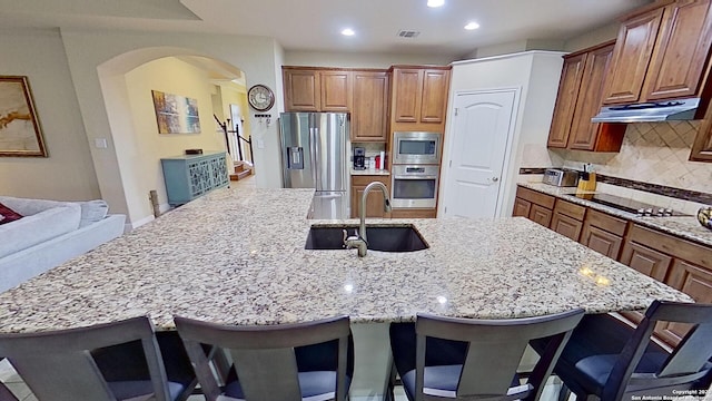 kitchen featuring a kitchen breakfast bar, sink, a spacious island, and appliances with stainless steel finishes