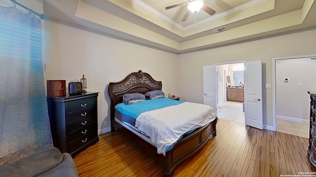 bedroom featuring a raised ceiling, connected bathroom, ceiling fan, and ornamental molding