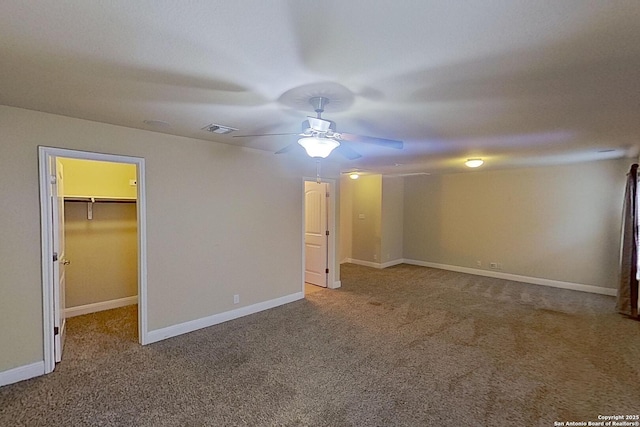 interior space featuring a walk in closet, ceiling fan, a closet, and carpet