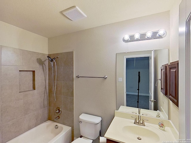 full bathroom with vanity, tiled shower / bath, and toilet