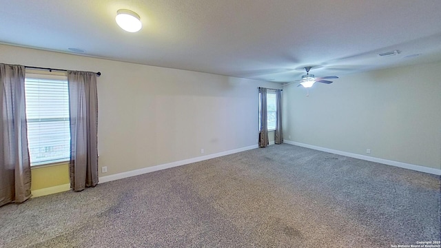 carpeted empty room with ceiling fan and plenty of natural light