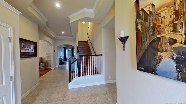 corridor with a raised ceiling, crown molding, and light tile patterned flooring