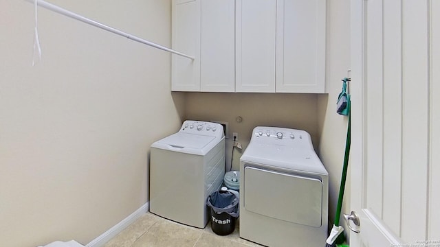 laundry area featuring washing machine and dryer, light tile patterned floors, and cabinets