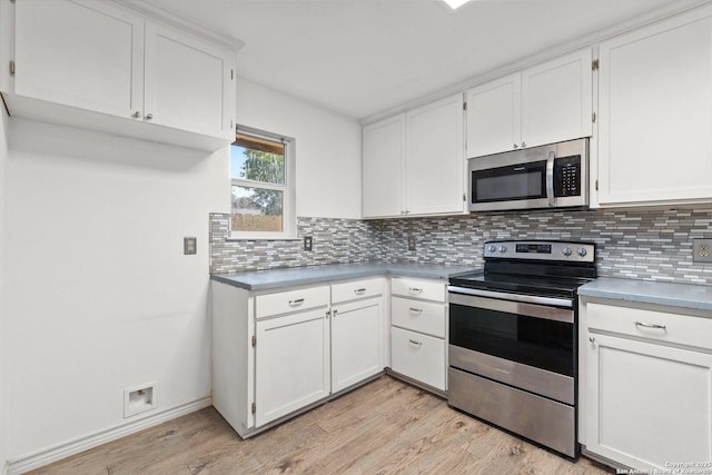 kitchen featuring decorative backsplash, white cabinets, light wood-type flooring, and appliances with stainless steel finishes