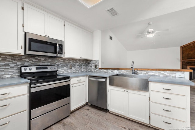 kitchen with kitchen peninsula, sink, white cabinetry, and stainless steel appliances