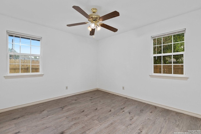 empty room featuring ceiling fan, light hardwood / wood-style floors, and a wealth of natural light