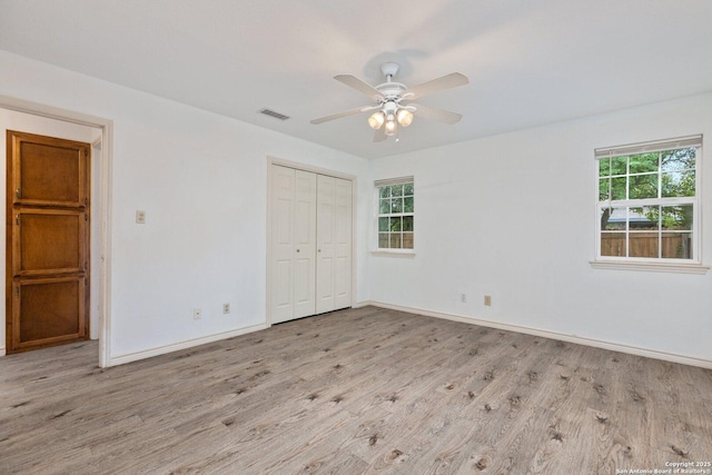 unfurnished bedroom with ceiling fan, light wood-type flooring, and a closet