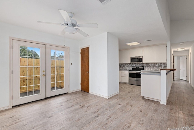 kitchen with decorative backsplash, kitchen peninsula, stainless steel appliances, white cabinets, and a breakfast bar area