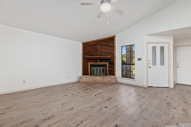 unfurnished living room with ceiling fan, light wood-type flooring, lofted ceiling, and a fireplace