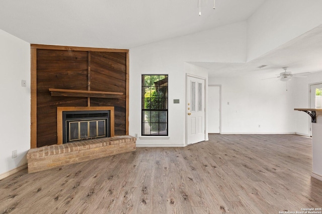 unfurnished living room featuring ceiling fan, a fireplace, high vaulted ceiling, and hardwood / wood-style floors