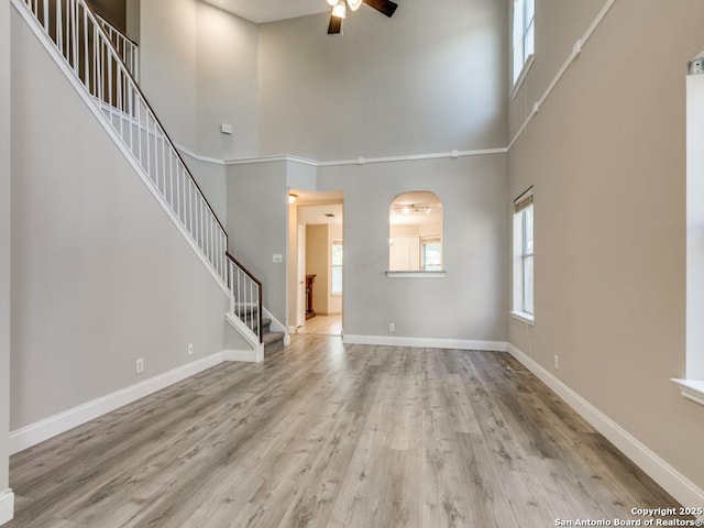 unfurnished living room featuring a high ceiling, light hardwood / wood-style flooring, and ceiling fan