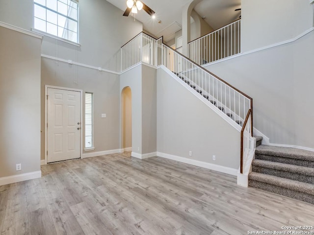 entrance foyer featuring light wood-type flooring, a towering ceiling, and ceiling fan