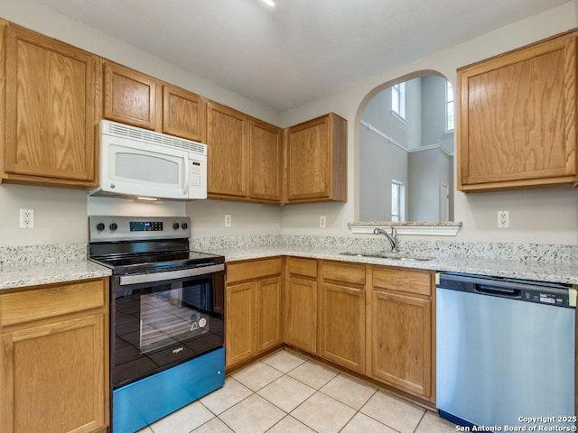 kitchen with light stone countertops, sink, light tile patterned floors, and stainless steel appliances