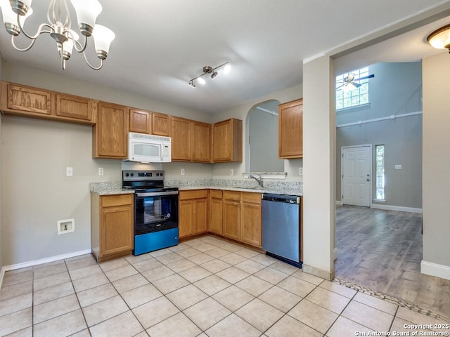 kitchen with pendant lighting, ceiling fan with notable chandelier, sink, appliances with stainless steel finishes, and light tile patterned flooring