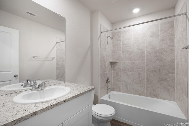 full bathroom featuring toilet, tiled shower / bath, and vanity