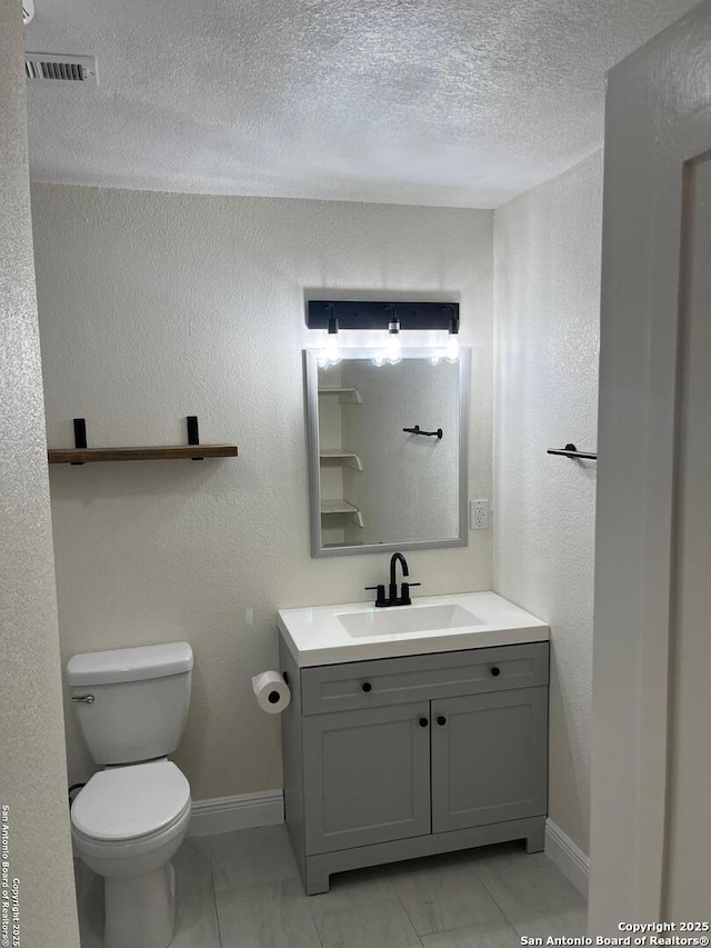 bathroom featuring a textured ceiling, vanity, and toilet