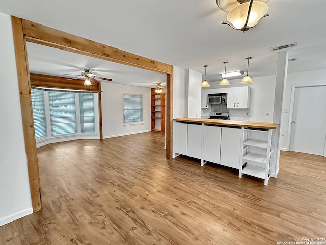 kitchen featuring white cabinets, light wood-type flooring, butcher block countertops, decorative light fixtures, and range