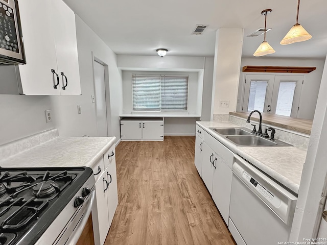 kitchen featuring sink, hanging light fixtures, appliances with stainless steel finishes, light hardwood / wood-style floors, and white cabinetry