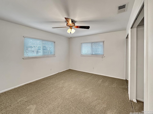 unfurnished bedroom with dark colored carpet, ceiling fan, and multiple windows