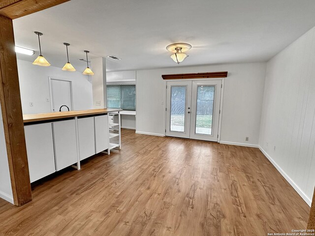 kitchen with pendant lighting, light hardwood / wood-style floors, and french doors