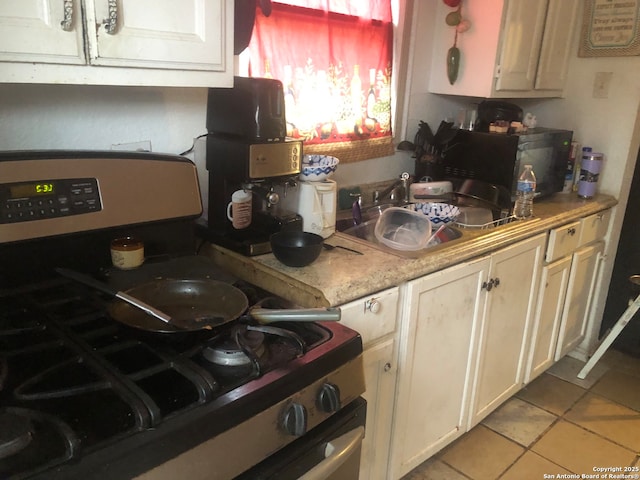 kitchen featuring gas stove, sink, and light tile patterned flooring