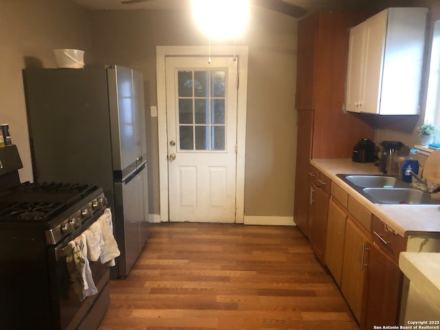 kitchen featuring sink, gas stove, and light wood-type flooring