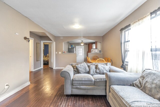 living room featuring dark wood-type flooring and ceiling fan