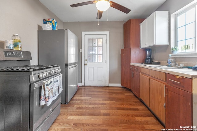 kitchen featuring sink, ceiling fan, appliances with stainless steel finishes, light hardwood / wood-style floors, and white cabinets