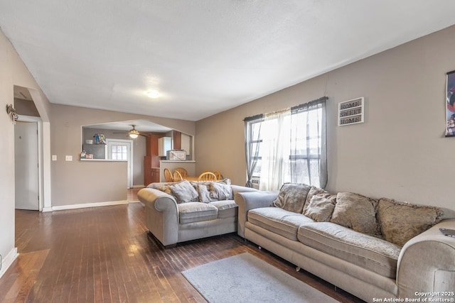 living room featuring dark wood-type flooring and ceiling fan