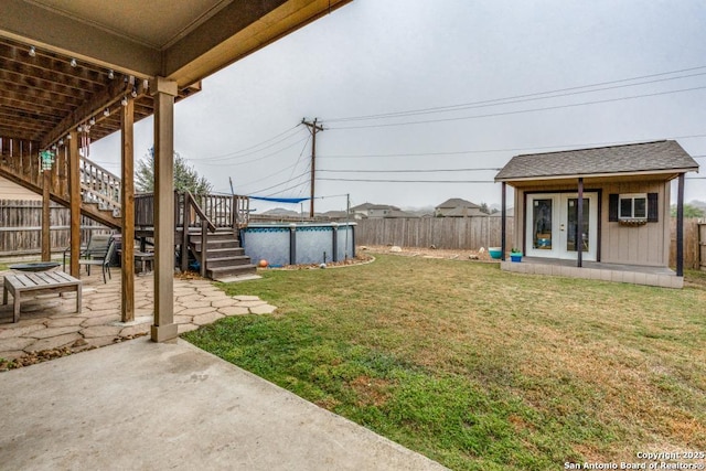 view of yard with a swimming pool side deck, an outbuilding, a patio, and french doors