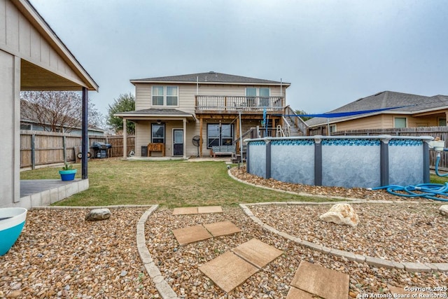 back of property with a yard and a fenced in pool