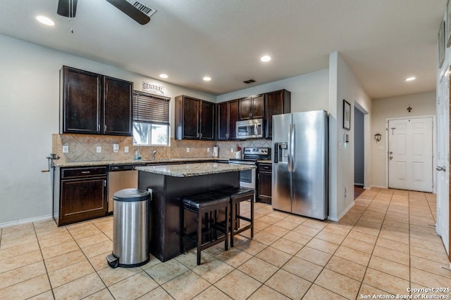 kitchen with a center island, a breakfast bar area, tasteful backsplash, dark brown cabinets, and stainless steel appliances