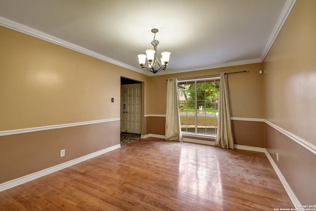 empty room with a notable chandelier, wood-type flooring, and ornamental molding