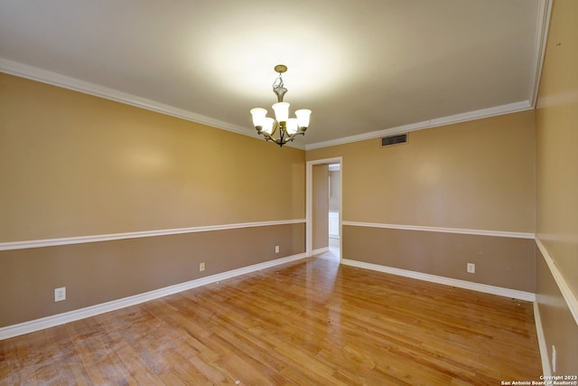 empty room featuring hardwood / wood-style flooring, ornamental molding, and an inviting chandelier