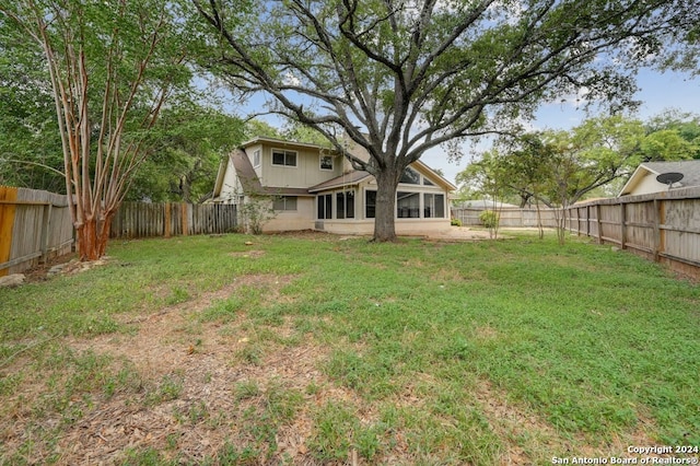 view of yard featuring a sunroom and a fenced backyard