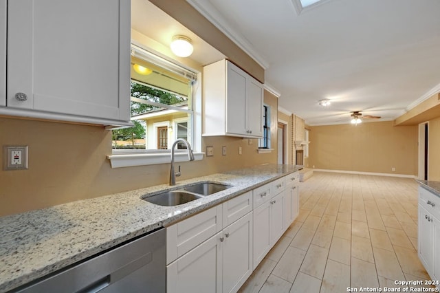 kitchen featuring light stone countertops, stainless steel dishwasher, ceiling fan, sink, and white cabinetry