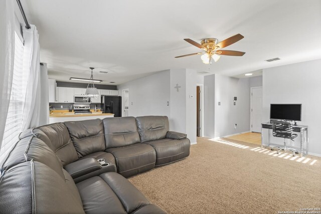 carpeted living room with ceiling fan