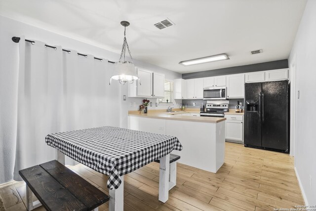 kitchen with kitchen peninsula, white cabinets, stainless steel appliances, and decorative light fixtures