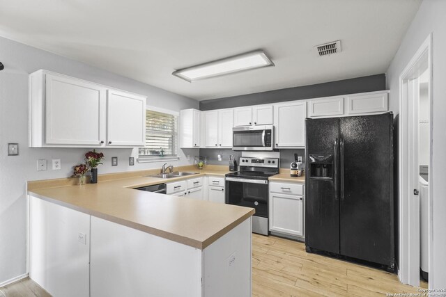 kitchen featuring kitchen peninsula, appliances with stainless steel finishes, sink, white cabinets, and light hardwood / wood-style floors