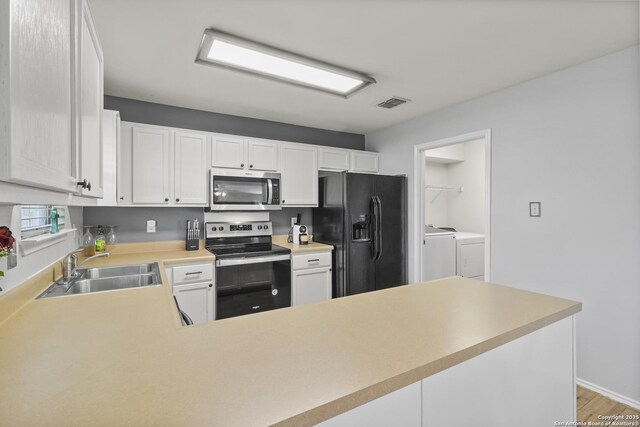 kitchen with independent washer and dryer, kitchen peninsula, sink, and appliances with stainless steel finishes