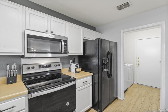 kitchen with washer and clothes dryer, white cabinets, light hardwood / wood-style floors, and appliances with stainless steel finishes