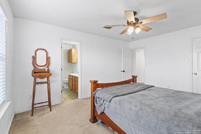 bedroom with ceiling fan, light colored carpet, and ensuite bathroom