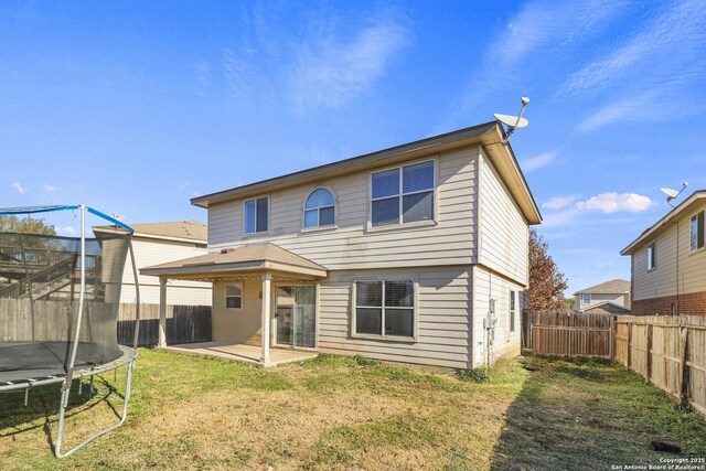 rear view of house featuring a patio, a trampoline, and a lawn