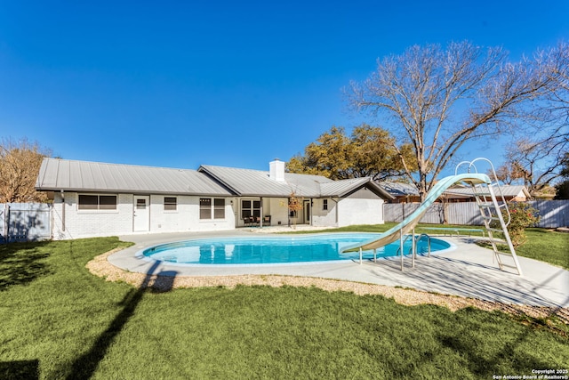 view of swimming pool featuring a lawn, a patio, and a water slide