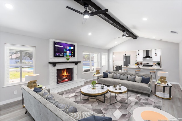 living room featuring ceiling fan, light hardwood / wood-style floors, a healthy amount of sunlight, and a fireplace