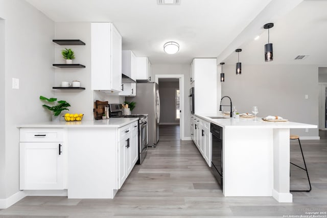 kitchen featuring white cabinetry, sink, light hardwood / wood-style floors, decorative light fixtures, and black appliances